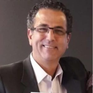 CEO da Sevensete, Roberto Pina, de terno sorrindo em uma parede preta
